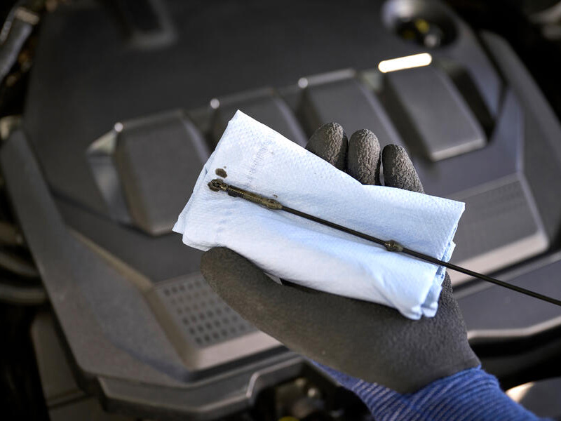 Comprobación del nivel de aceite de motor con varilla y papel de taller durante una revisión técnica